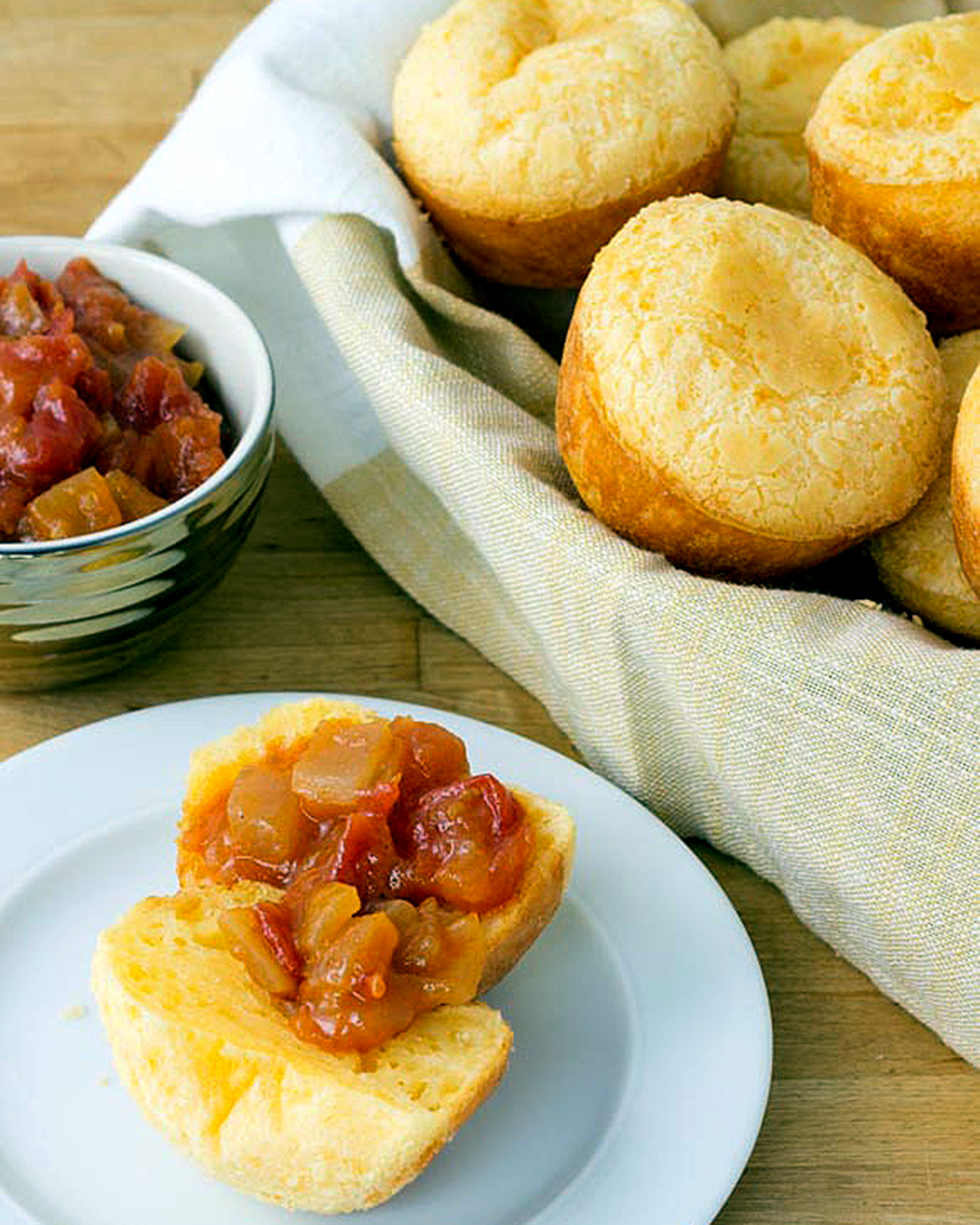 A photo of cheese puffs in a basket and an open cheese puff topped with tomato jam.